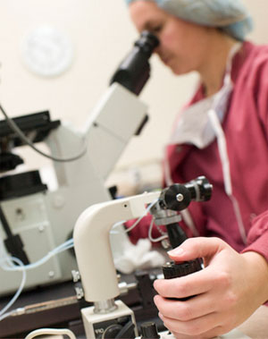 Lab Technician Looking through Microscope